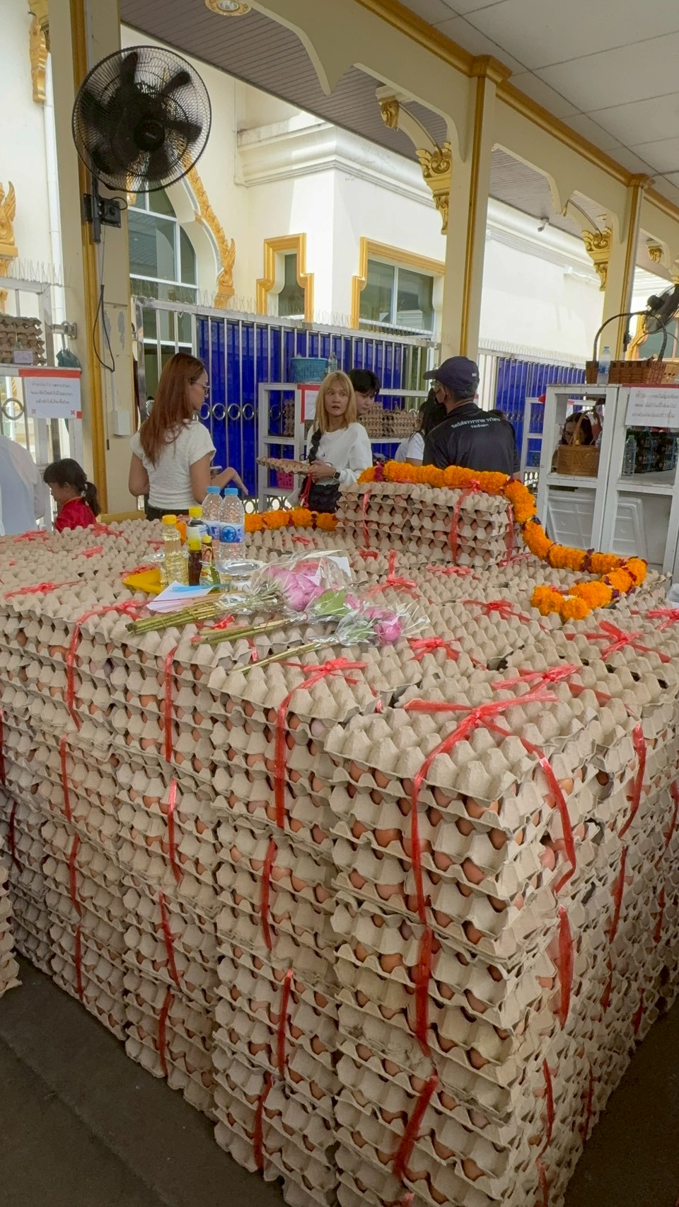 กองไข่ต้มชุดใหญ่ผูกริบบิ้นพร้อมมาลัยดาวเรืองที่ศาลาวัด